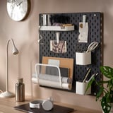 Das an der Wand montierte SKÅDIS Steckbrett organisiert Büromaterial und hält Scheren, Stifte, Papierrollen und Notizen in einem stilvollen und funktionalen Setup.