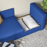 Blaues Schlafsofa mit erhöhter Armlehne, das den Blick auf den Stauraum im Inneren freigibt.