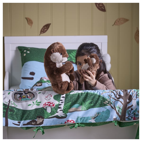 Mädchen umarmt Otter-Plüschtiere auf einem Bett mit Naturmotiven.