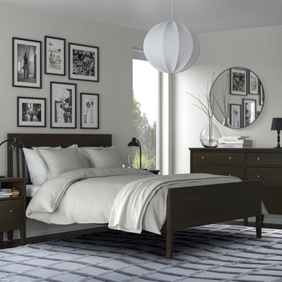 Modernes Schlafzimmer mit schwarz-weißem Dekor, grauem SKUGGSVINGEL-Teppich, schwarzem Bett und Kommode, weißer Beleuchtung.