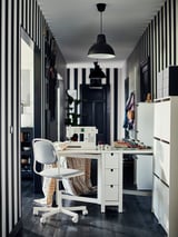 Modernes Homeoffice mit schwarz-weißem Dekor, mit weißem Schreibtisch, grauem Stuhl, Nähmaschine und einer schwarzen SKURUP-Pendelleuchte.