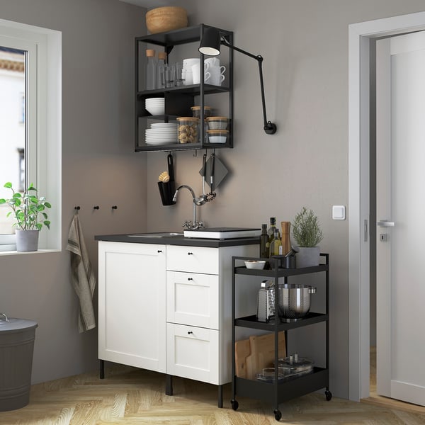 Moderne Küche mit SKYDRAG-Leuchten, schwarzem Wasserhahn, weißen Theken und Grün.