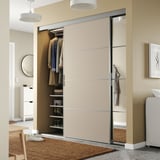 Moderner Kleiderschrank mit SKYTTA Glasschiebetür, Kleidung, Regalen und runden Lichtern in gemütlichem Raum.