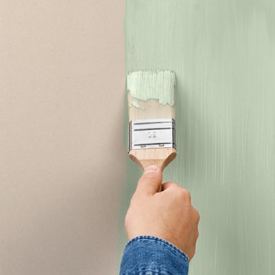 Handbemalung der Wand mit hellgrüner Farbe mit einem Pinsel.