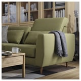Olivgrünes SLATORP-Sofa mit Holzbeinen, dunkler Decke, Kaffeetasse und geometrischem Teppich, gemütliche, moderne Wohnzimmereinrichtung.