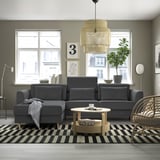 Modernes Wohnzimmer mit grauer SLATORP-Sektion, schwarz-weißem Teppich, Couchtisch aus Holz, Korbstuhl, großen Fenstern und stilvoller Pendelleuchte.