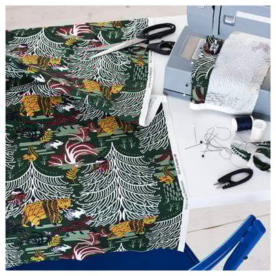 Ein Basteltisch mit Nähmaschine, buntem Stoff, Schere, Garn und Stecknadeln.