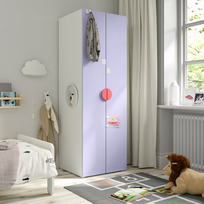 Ein Kinderzimmer mit einem hohen SMÅSTAD-Kleiderschrank, einem Pullover, einem Teddybären und Büchern.