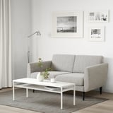 Sofa im modernen Wohnzimmer mit Lampe, Couchtisch und Blumen.