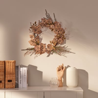 Ein getrockneter Blumenkranz hängt an einer Wand über einem Schrank und zeigt natürliche, recycelte Dekorationen.