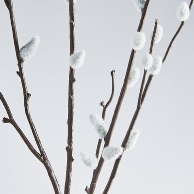 Künstliche Zweige mit flauschigen weißen Knospen, realistisch vor einem hellen Himmel angeordnet.