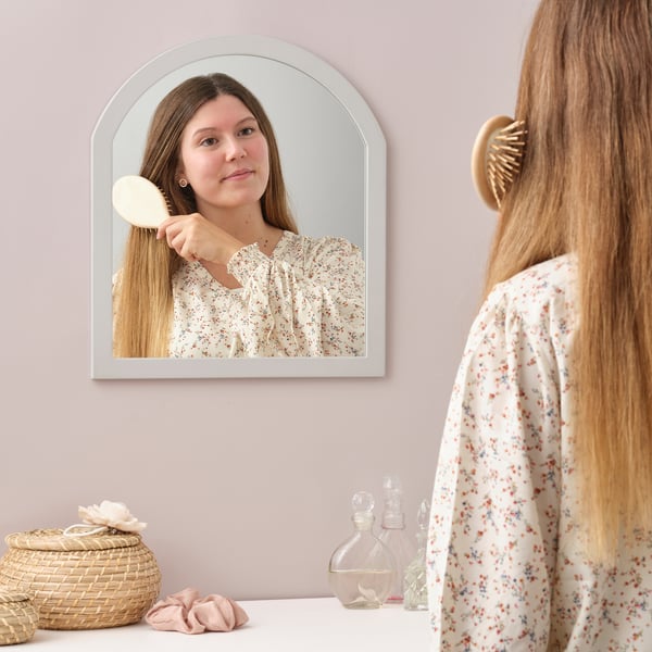 Mädchen bürstet Haare im Spiegel, Blumenkleid, Korb, Flaschen.