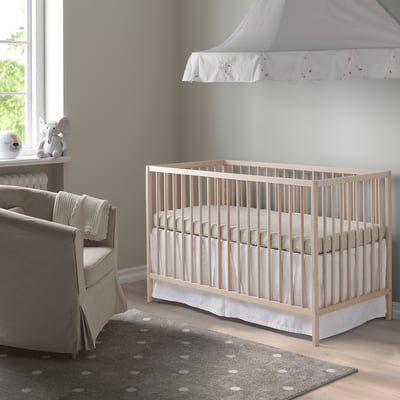 SNIGLAR Kinderbett aus Holz mit verstellbarer Höhe im Kinderzimmer. Umgeben von grauem Sessel, gepunktetem Teppich, kleinem Tisch mit Lampe und Spielzeug.