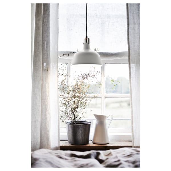 Fenster mit einer Hängelampe, einer Topfpflanze und einer weißen Vase auf dem Fensterbrett, die auch als Krug verwendet wird.