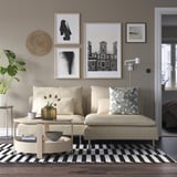 Modernes Wohnzimmer mit grauem SÖDERHAMN-Sofa, schwarz-weißem Teppich, Kunstwand, Pflanzen und schickem Dekor.