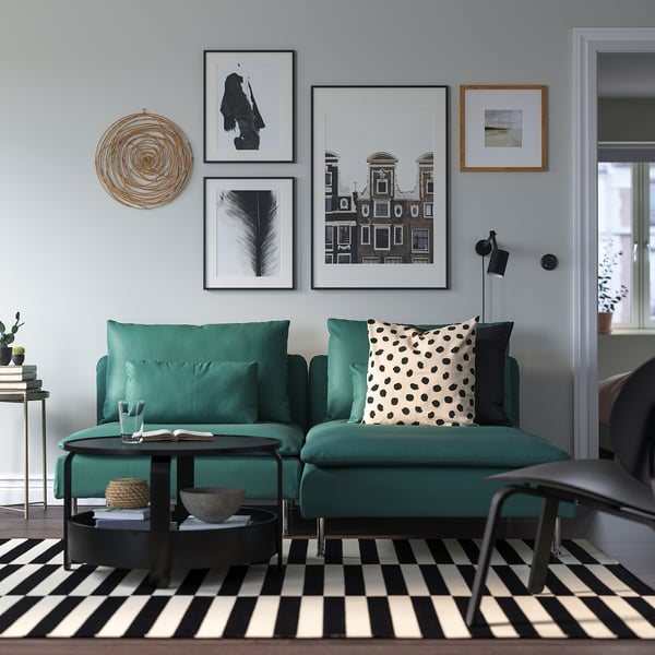 Modernes Wohnzimmer mit blaugrünem SÖDERHAMN-Sofa auf kariertem Teppich, Kissen, Kunst oben, Beistelltisch mit Buch und Korb.