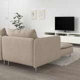 Modernes beiges Sofa mit Chaiselongue, weißer Wand, TV-Einheit, Pflanze.