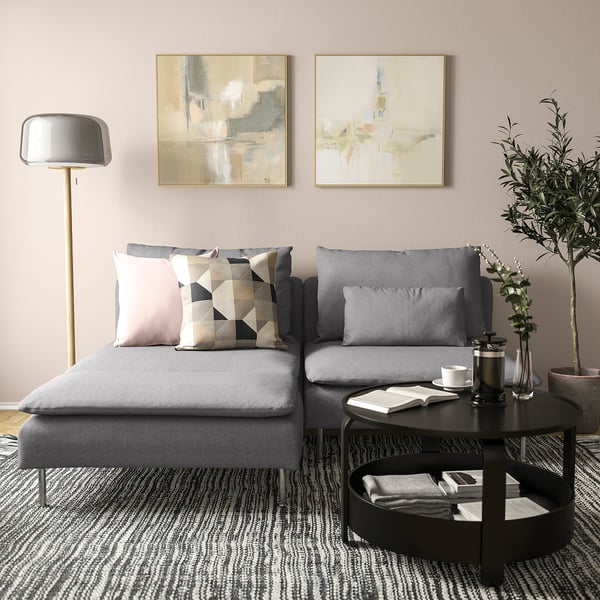 Modernes Wohnzimmer mit grauem SÖDERHAMN-Sofa, rosa und gemusterten Kissen, schwarzem Couchtisch und abstrakter Wandkunst.