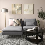 Modernes Wohnzimmer mit grauem SÖDERHAMN-Sofa, rosa und gemusterten Kissen, schwarzem Couchtisch und abstrakter Wandkunst.
