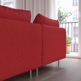 Rotes modernes Sofa mit hohen Beinen im Wohnraum am Fenster.