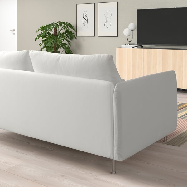 Modernes Wohnzimmer mit weißem L-förmigem Sofa, Holzboden, TV und Pflanze.