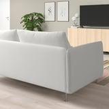 Modernes Wohnzimmer mit weißem L-förmigem Sofa, Holzboden, TV und Pflanze.