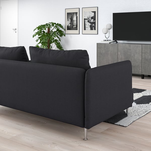 Modernes, minimalistisches Wohnzimmer mit großem schwarzen SÖDERHAMN-Sofa, grauem Teppich und schwarzem Fernseher.