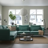 Modernes Wohnzimmer mit türkisfarbener SÖDERHAMN-Sektion, Kissen, Couchtisch, Fenster, Pflanzen.