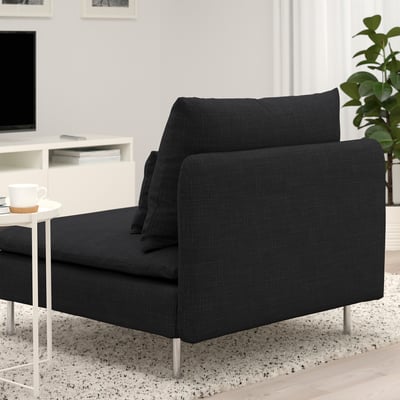 Schwarzes modernes Sofa mit tiefen Sitzgelegenheiten und Metallbeinen, positioniert in einem gemütlichen Wohnzimmer. Daneben steht ein Beistelltisch mit einer Kaffeetasse.