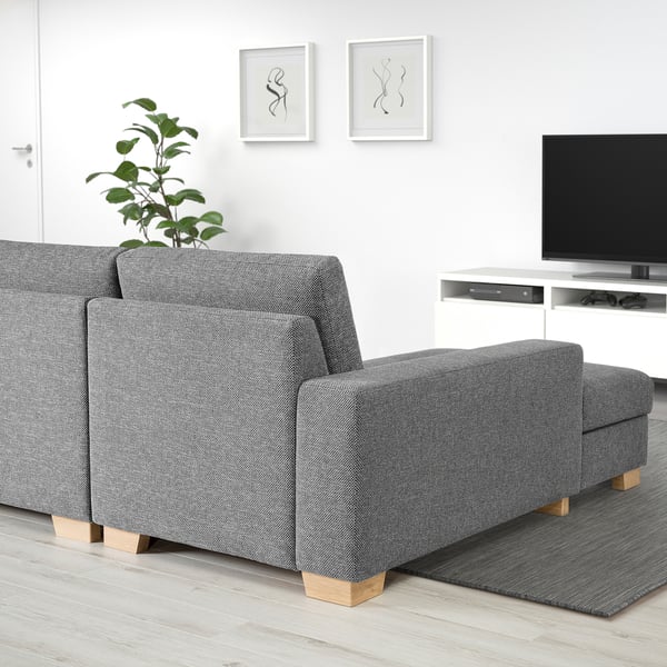 Modernes graues Sofa mit Chaiselongue, minimalistischer Stil, helle Holzbeine, in einem sauberen, hellen Wohnraum gelegen.