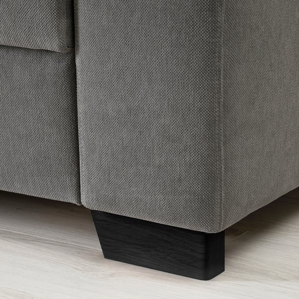 Nahaufnahme einer modernen dunkelgrauen Sofaecke, die ihr schlankes Design und ihr robustes Holzbein zeigt.