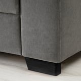Nahaufnahme einer modernen dunkelgrauen Sofaecke, die ihr schlankes Design und ihr robustes Holzbein zeigt.