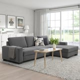 Moderne graue L-förmige Sofagarnitur mit hölzernem Couchtisch in einem hellen Wohnzimmer.