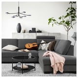 Modernes graues Sofa mit Kissen und Decke, rundem Couchtisch aus Glas, Gitarre und trendiger Beleuchtung.