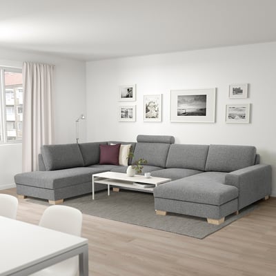 Modernes Wohnzimmer mit großem L-förmigen grauen SÖRVALLEN-Sofa, weißem Couchtisch und Schwarz-Weiß-Fotos an der Wand.
