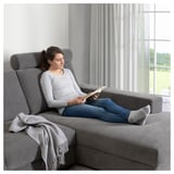 Eine lesende Frau auf einer grauen SÖRVALLEN-Couch am Fenster.