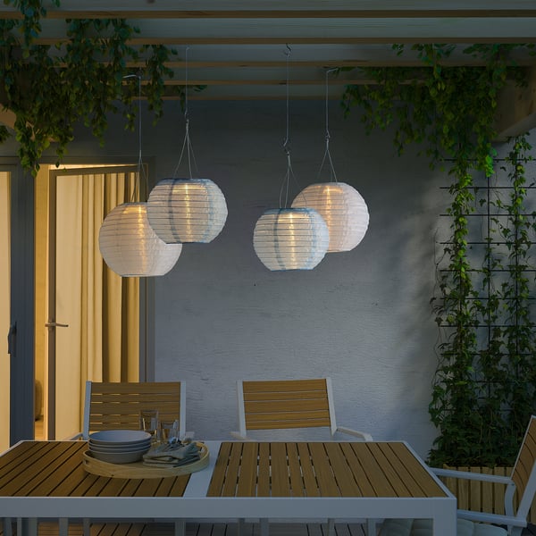 Esstisch für den Außenbereich mit SOLVINDEN Solarlaternen. Holzstühle, Teller, Utensilien. Sanftes Abendleuchten.