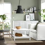 Modernes Wohnzimmer mit grünen Wänden, weißer Couch, Couchtisch und gestreiftem beige-schwarzem Teppich, STARREKLINTE.