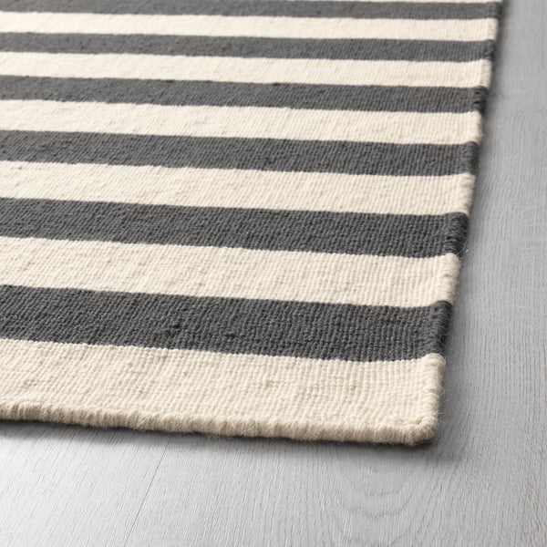 Nahaufnahme eines handgewebten Streifenteppichs mit abwechselnd grauen und weißen Streifen, der seine hochwertige Textur und Verarbeitung zur Geltung bringt.