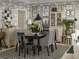 Modernes Esszimmer ein schwarzer Esstisch mit schwarzen Stühlen, gestreiftem Teppich, grauen Schränken, Pflanzen und künstlerischer Wanddekoration mit Blumentapete.