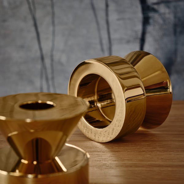 Kerzenständer aus goldenem Metall auf Holz; Einer hält Teelichter, der andere hohe Kerzen. Schwere, robuste Konstruktion.