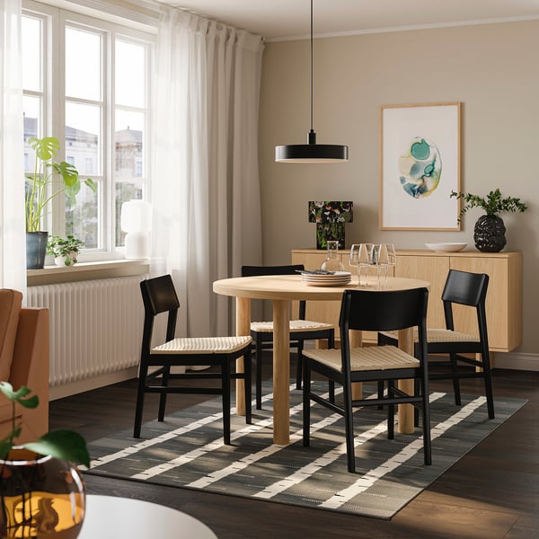 Kleines, rundes Esszimmer mit 4 schwarzen Stühlen unter einer schwarzen Pendelleuchte, perfekt für intime Zusammenkünfte.