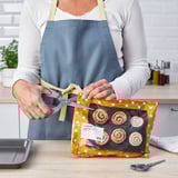Der Koch mit Schürze öffnet Zimtschnecken mit einer vielseitigen Schere.