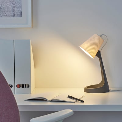 Moderne SVALLET-Lampe auf Schreibtisch mit Notizbuch, Ordner und Monitor. Wand hat gerahmtes Bild.