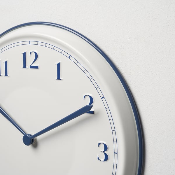 Moderne Wanduhr mit weißem Zifferblatt, blauen Akzenten und großen Ziffern; zeigt die Zeit mit 2:07 an.