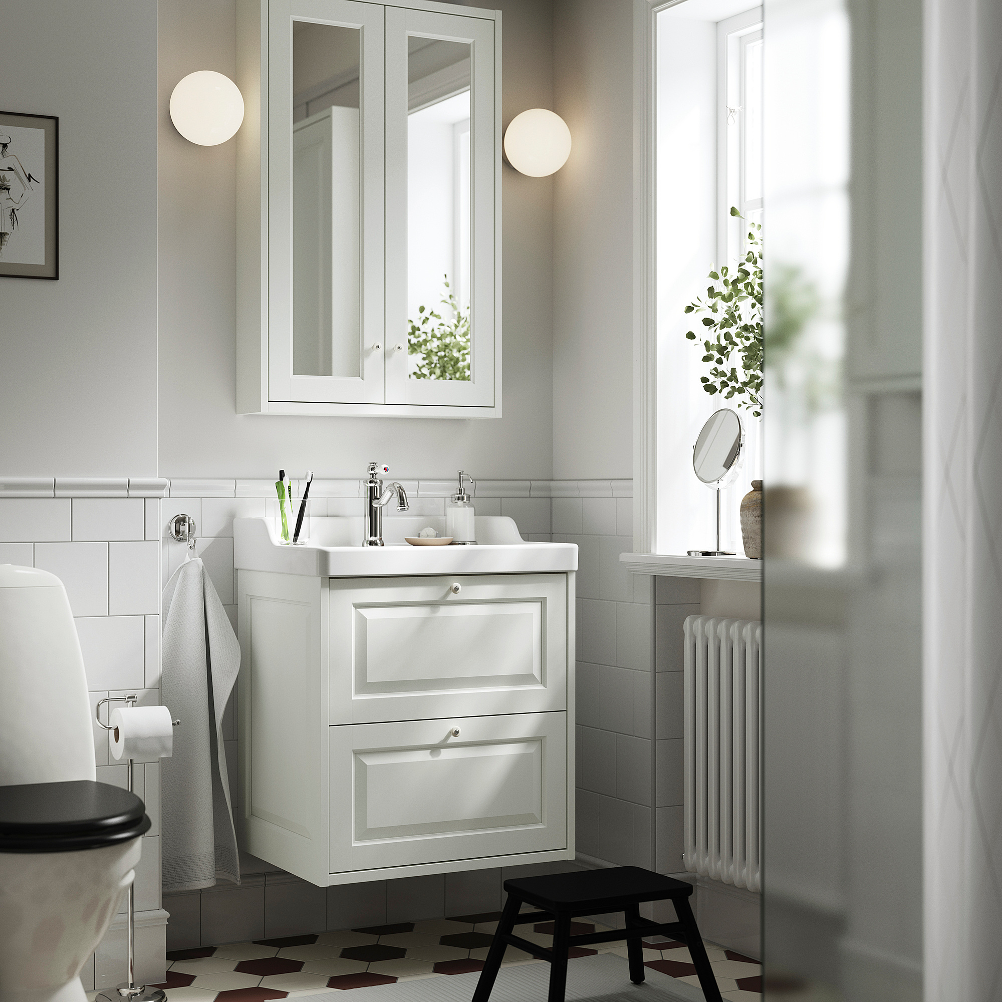 Ein weißer Waschtisch von TÄNNFORSEN mit 2 Schubladen, Spüle, Spiegelschrank und runden Leuchten. Enthält einen schwarzen Hocker und einen Handtuchheizkörper.