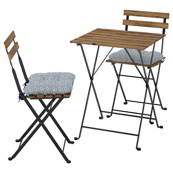 Klappbares Outdoor-Möbelset mit Holztisch und Stühlen, grauen Kissen, schwarzen Metallbeinen.