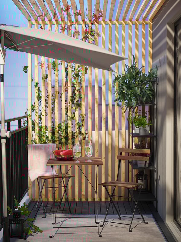Holzbalkon mit TÄRNÖ-Set, Wassermelone, Getränken, Hängepflanzen.