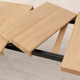 Ausziehbarer Esstisch aus Eiche mit Metallgestell, teilweise ausgezogen abgebildet, für zusätzliche Sitzgelegenheiten.