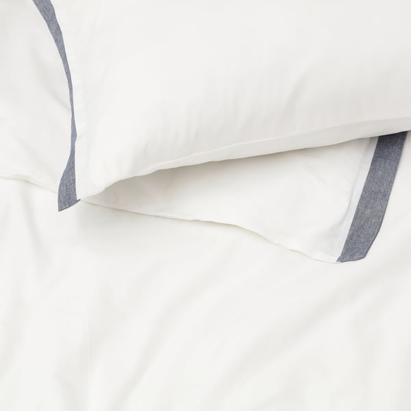 Strahlend weiße Bettwäsche mit elegantem blauem Besatz, der hochwertige Materialien und sorgfältige Verarbeitung präsentiert.